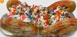 Churro split con helado, chantilly y confites de colores.